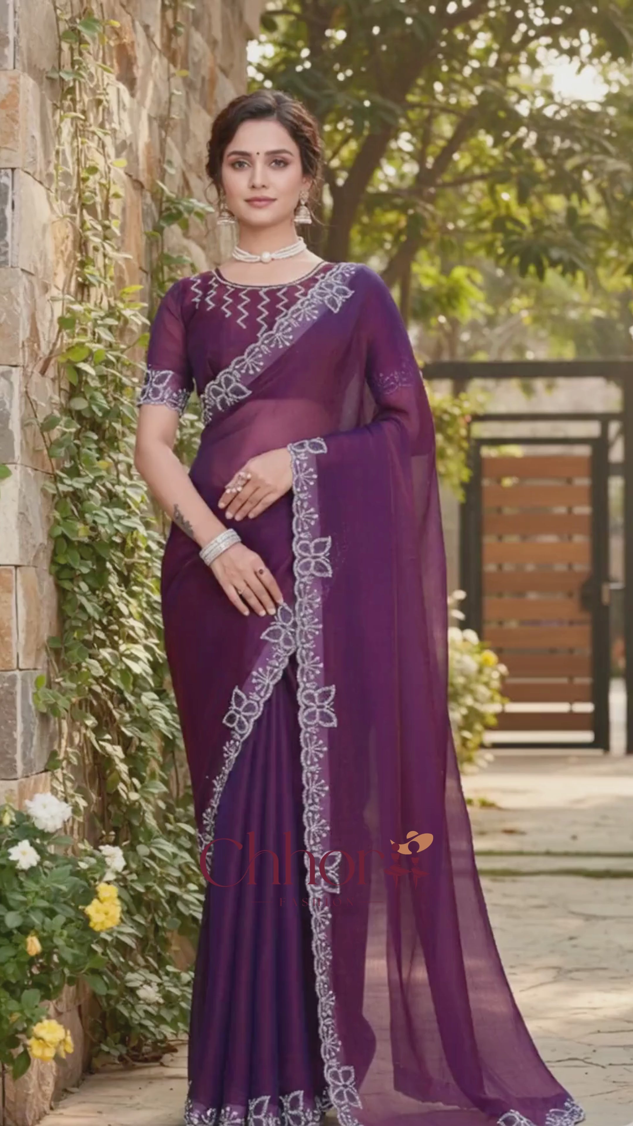 Woman wearing a purple saree with a stone wall and greenery in the background | Chhorii Fashion